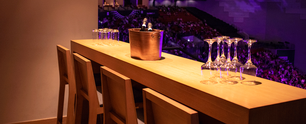 Suite Experience - Premium seating area inside the first direct bank arena overlooking the arena bowl with champagne, glassware and ambient purple lighting. First Direct Bank Arena – 1180 x 480 px